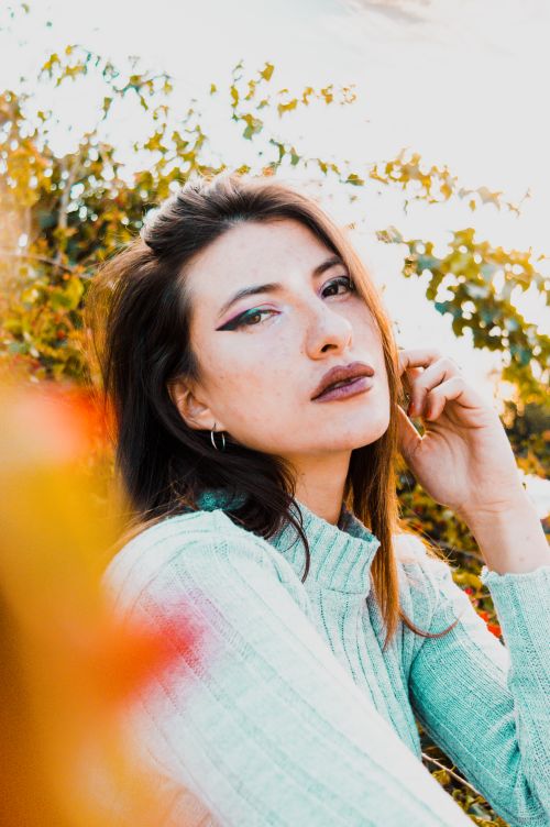 Free Portrait of a woman with artistic makeup in a natural outdoor setting, captured in vibrant colors. Stock Photo