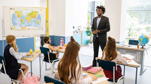 Teacher engaging with students in a bright, modern classroom setting.