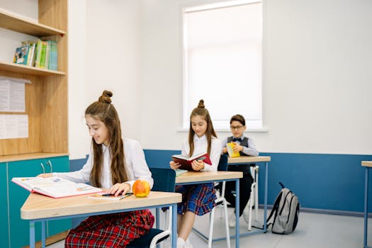Three children studying at desks in a bright, modern classroom.