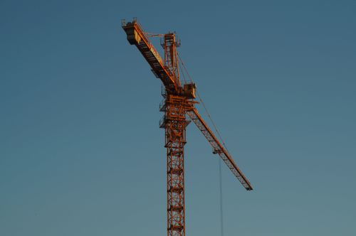 Free Tower crane silhouetted against a clear blue sky at sunset. Stock Photo