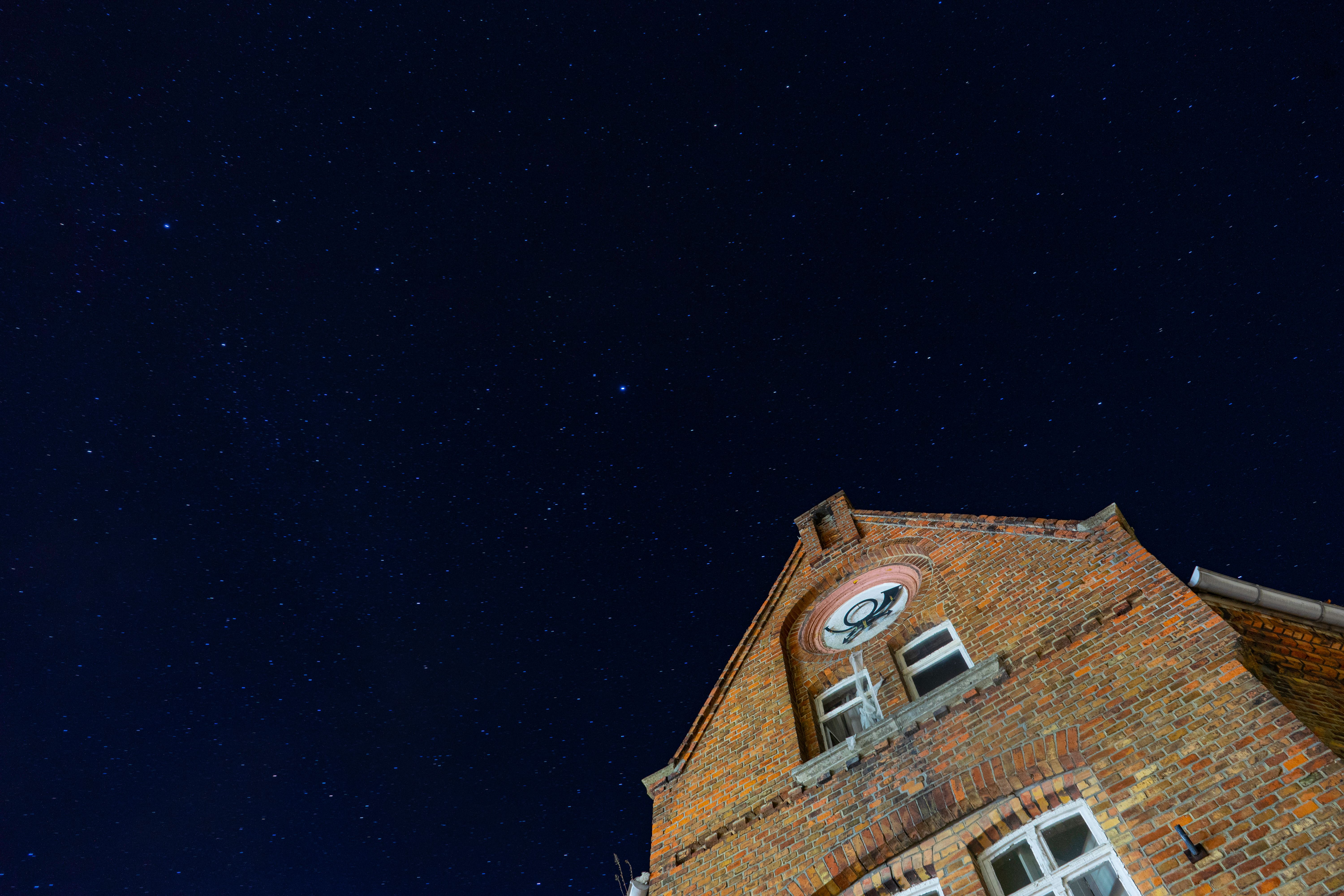 Veduta dal basso di un vecchio edificio in mattoni sullo sfondo di un cielo notturno stellato a Helbra, in Germania.