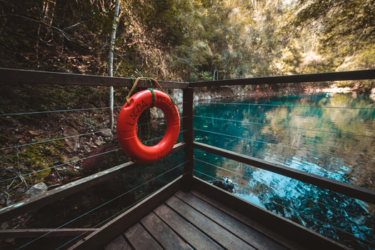 A serene view from a wooden deck overlooking Lagoa Misteriosa in Bonito, Brazil, with vibrant blue waters.