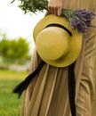 A Person Holding a Boater Hat and a Bunch of Lavenders