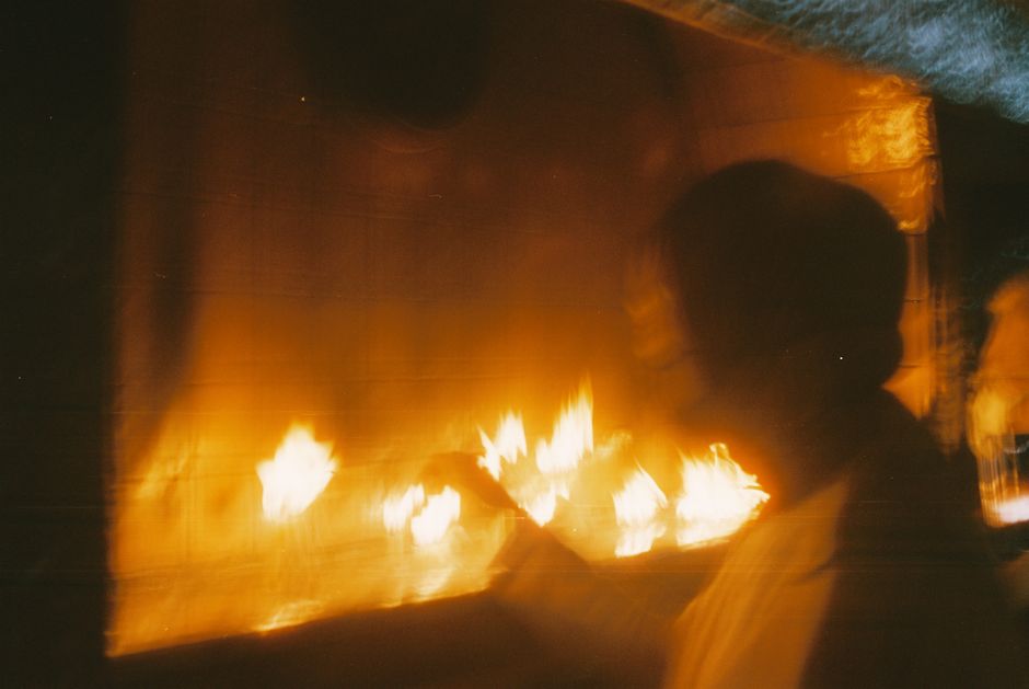 炎に手を伸ばすぼやけた人物の抽象的な画像で、神秘的で温かみのある感覚を呼び起こします。