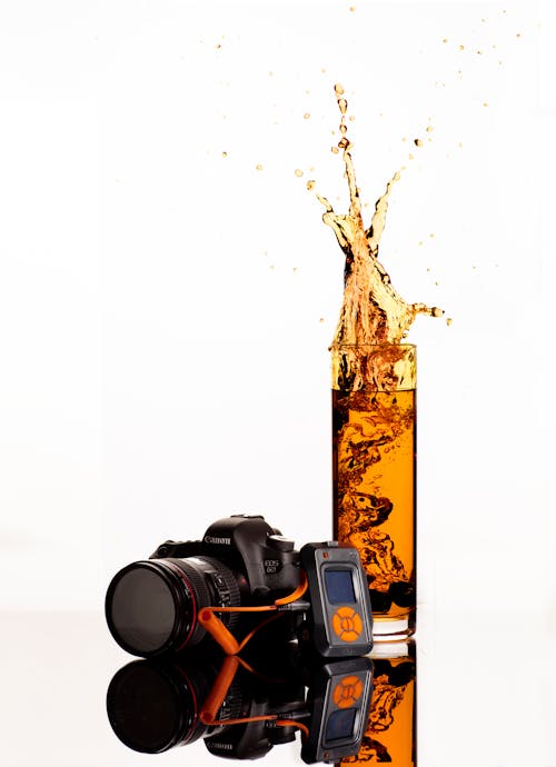 Black Canon Dslr Camera Behind Clear Highball Glass