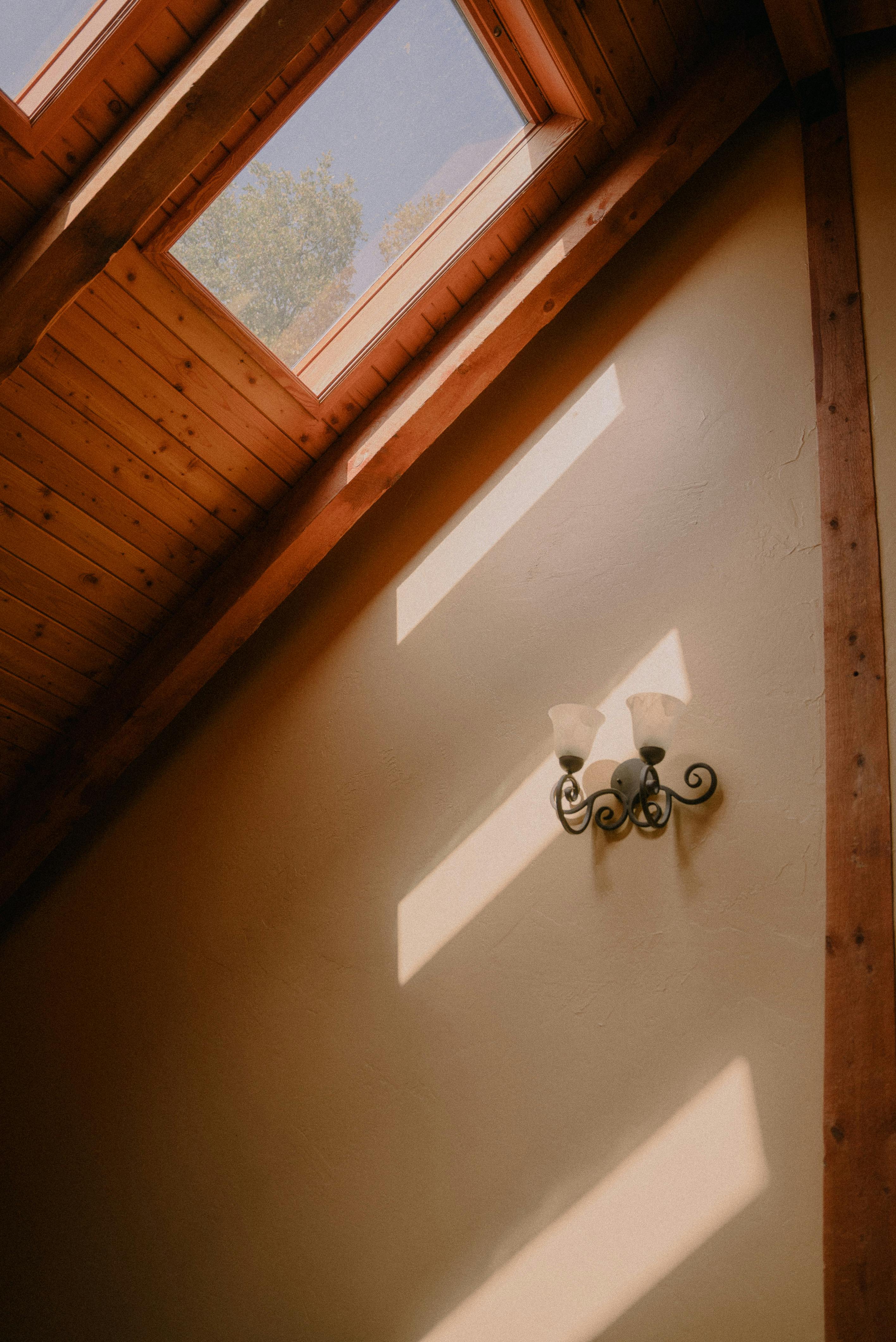 Warmly lit interior featuring a wooden ceiling and skylight highlighting the wall lamp.