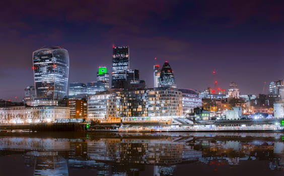 Beautiful cityscape of London at night with skyscrapers reflecting in the Thames River.