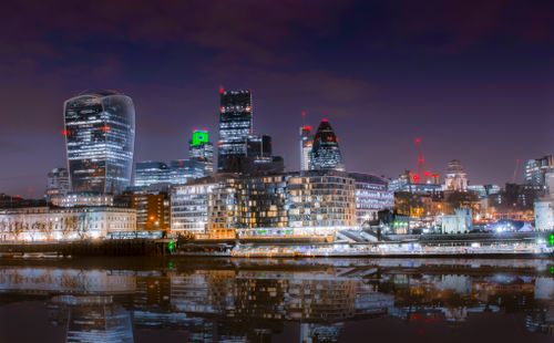 Free Beautiful cityscape of London at night with skyscrapers reflecting in the Thames River. Stock Photo