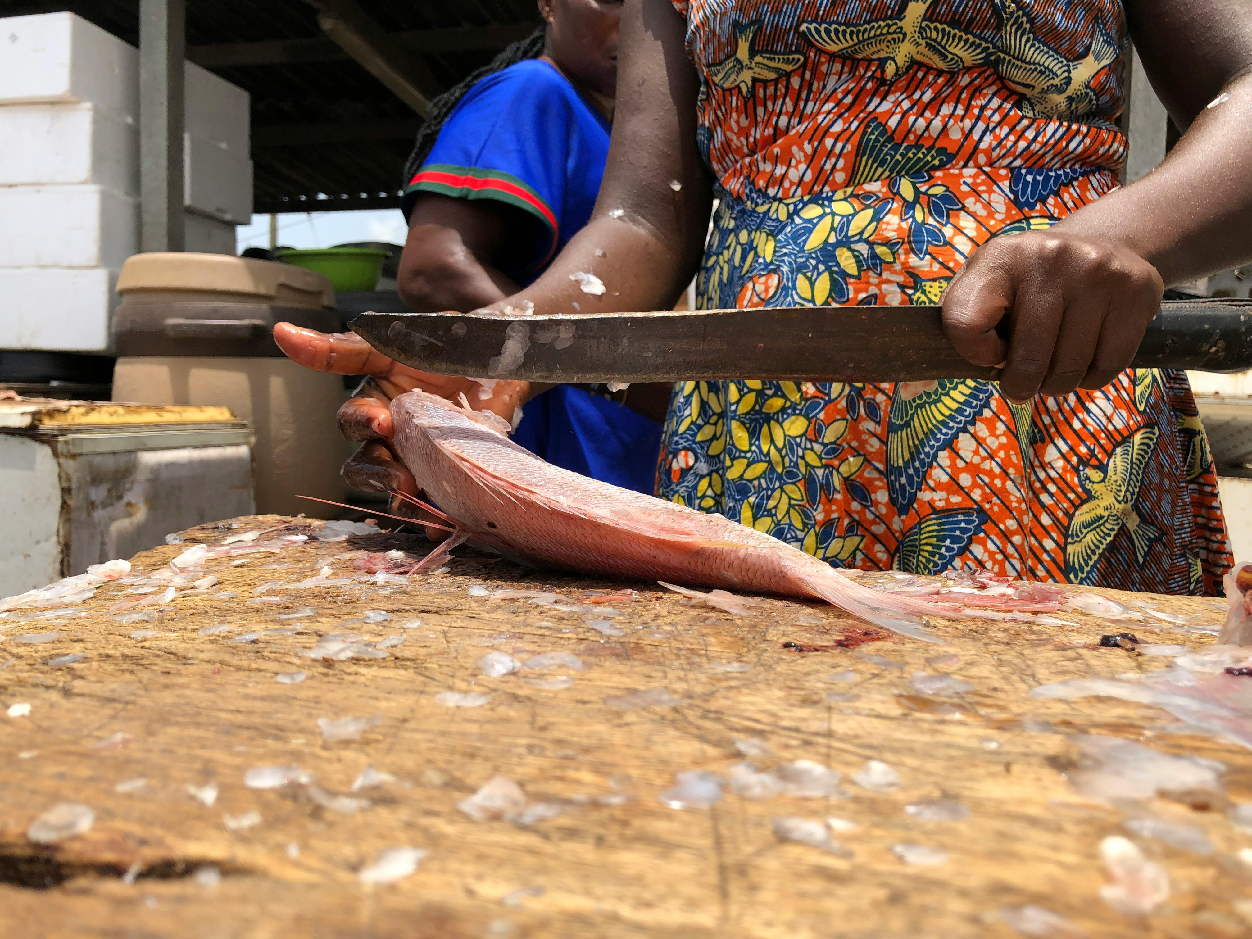 a woman cleaning a fish with a large knife