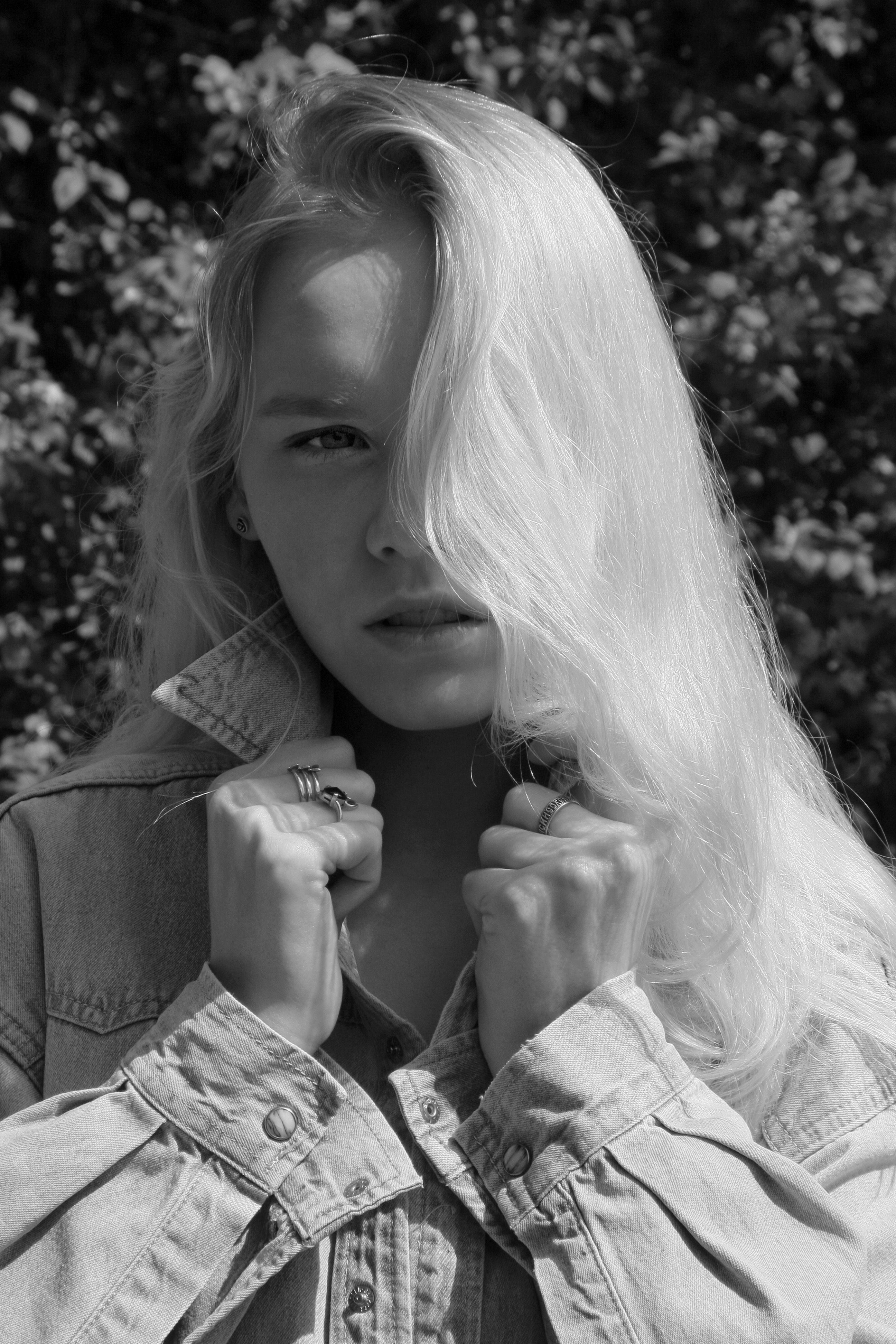 Artistic black and white portrait of a young woman outdoors, exuding intensity.