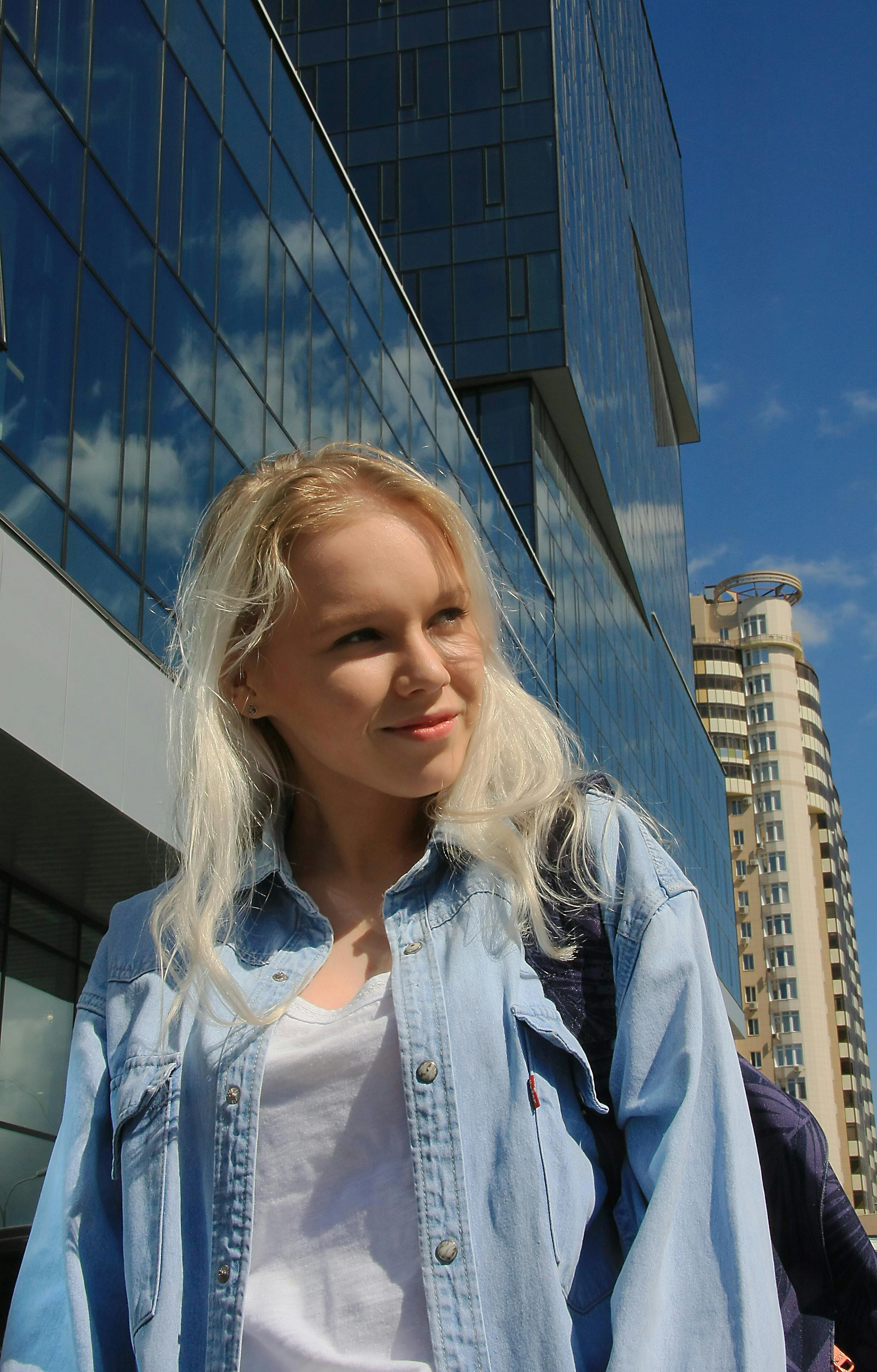 Portrait of a smiling young woman standing outdoors in a modern urban area with skyscrapers.