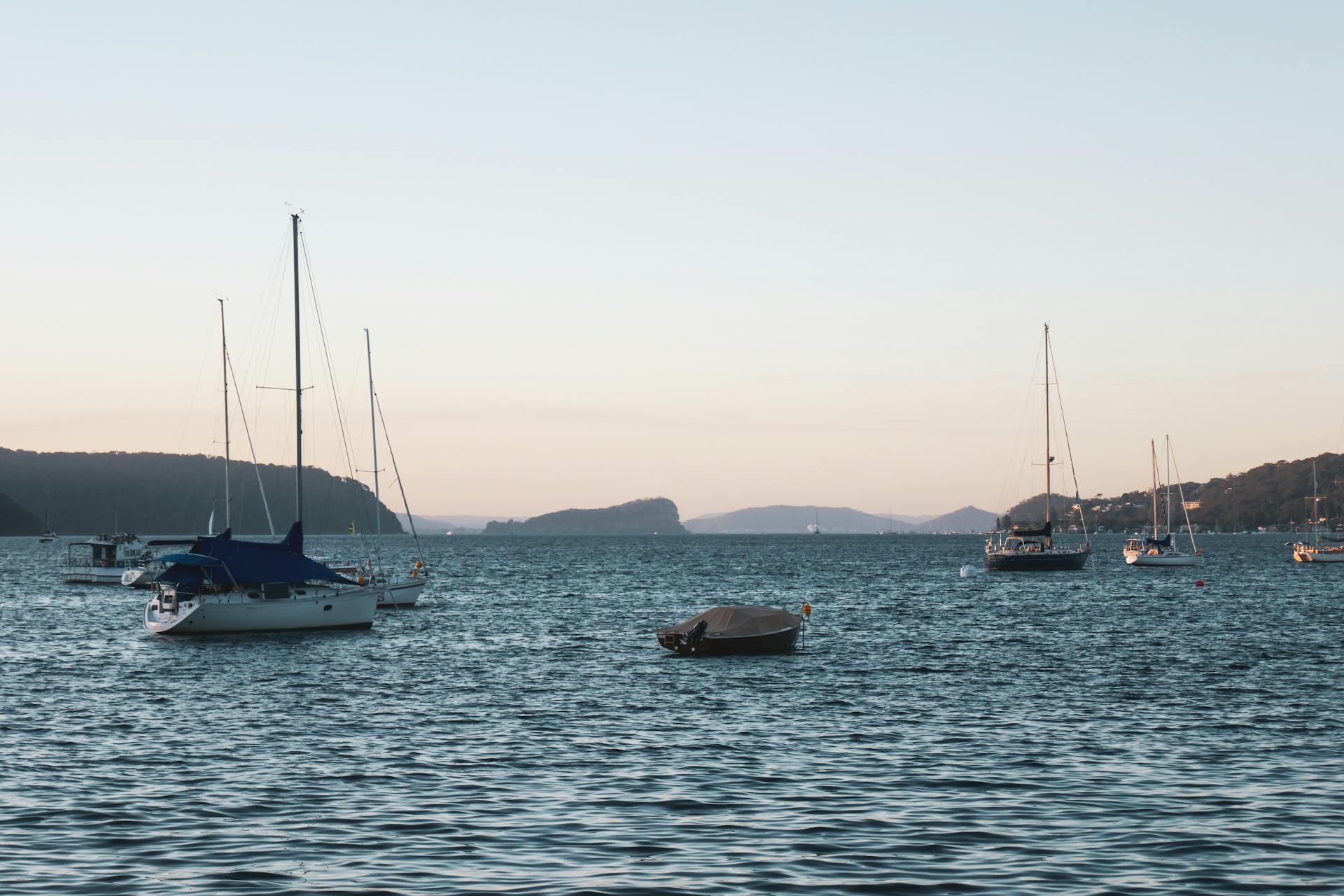 Sailboats gently sway on the calm waters of Palm Beach at sunset, Australia.