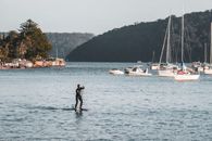 Woman in Black Wet Suit Standing on Body of Water