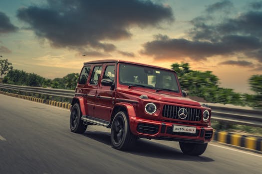 A red Mercedes SUV drives swiftly on a highway at sunset, showcasing luxury and speed.