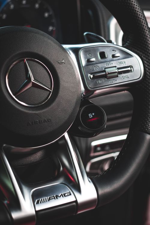 Free Detailed view of a premium car steering wheel showcasing controls and logo. Stock Photo