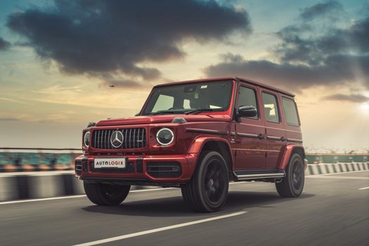 Red luxury SUV driving on a highway with a scenic sunset sky.