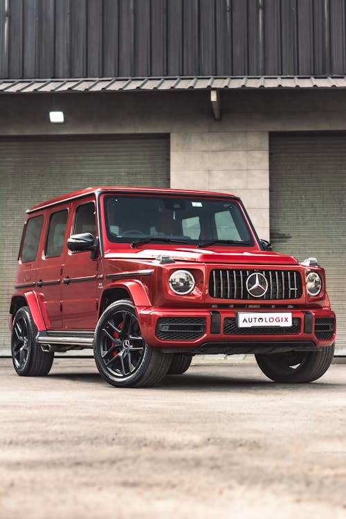 Free Red Mercedes Benz G Class Suv Parked Beside Brown Building Stock Photo