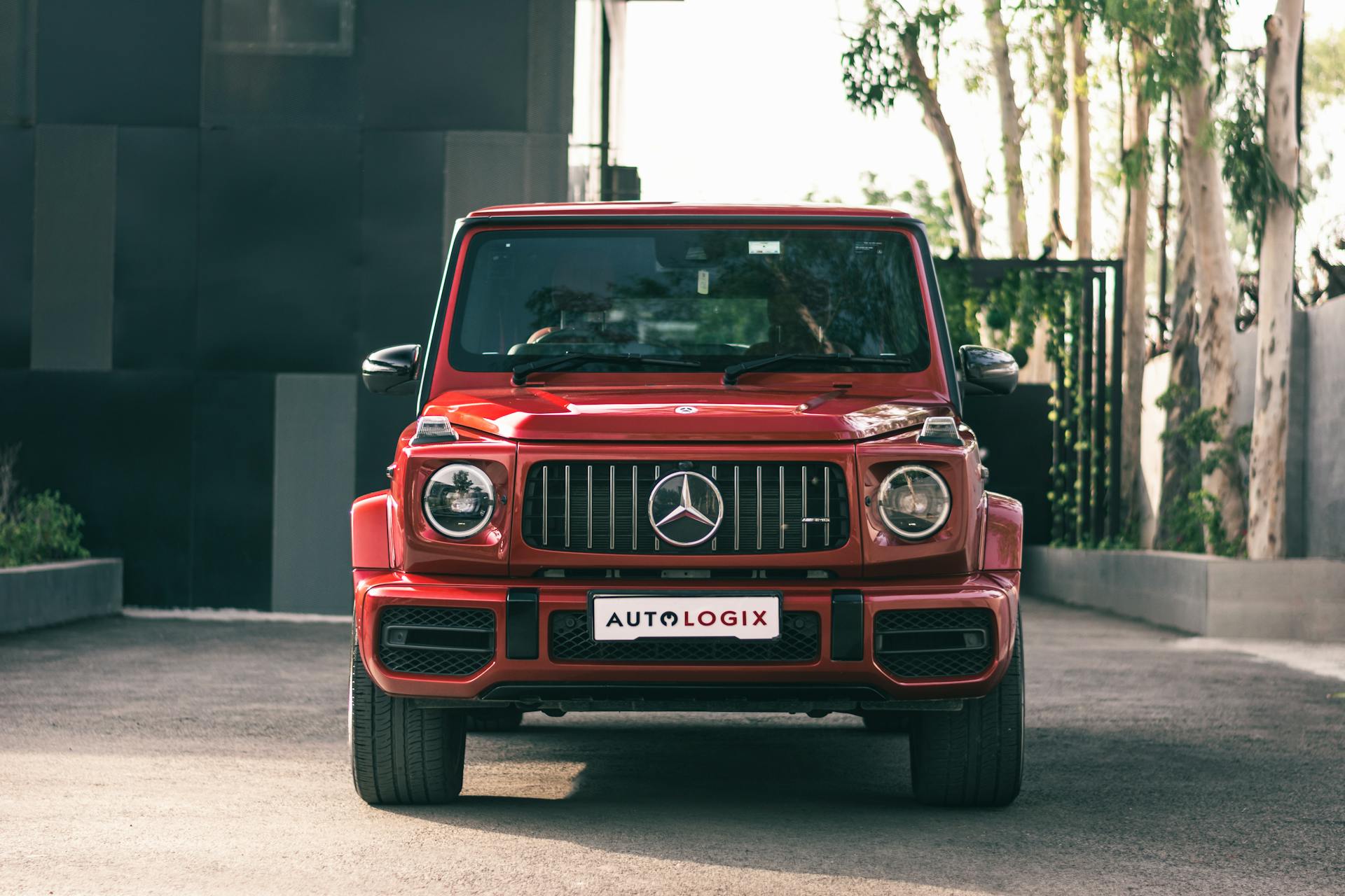 Front view of a luxurious red Mercedes G-Class SUV parked outdoors on a sunny day.