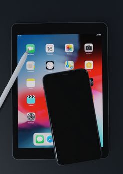 Flat lay of a smartphone and tablet with stylus on a dark background, highlighting modern technology.