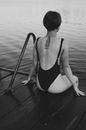 Woman in Black One Piece Swimsuit Sitting on Wooden Dock