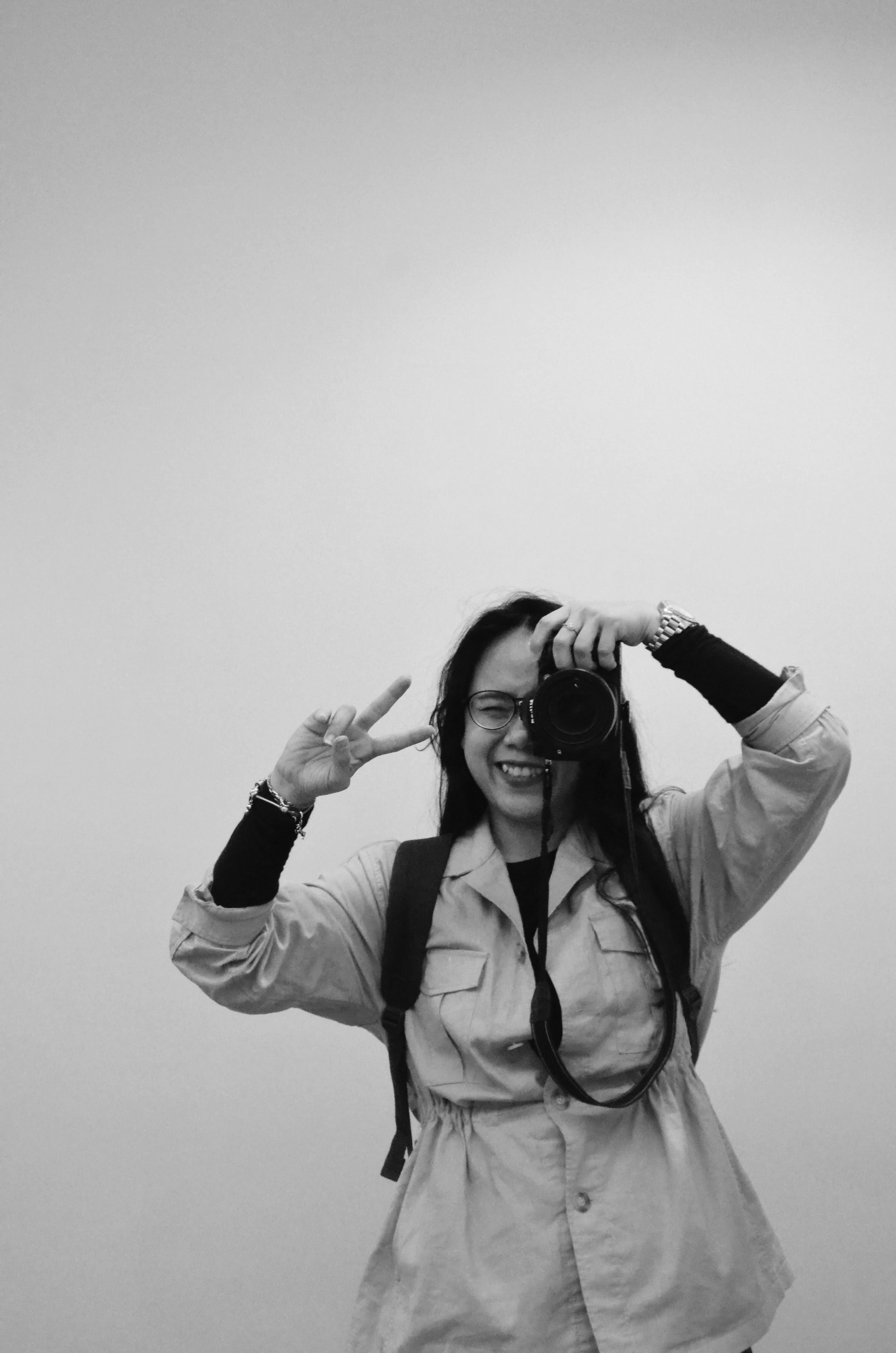 Monochrome portrait of a woman photographer posing with a camera.