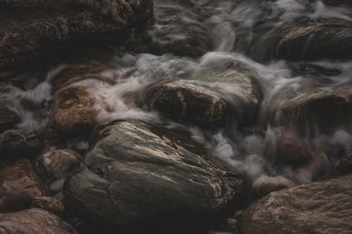Free Tranquil long exposure of a creek's flowing waters over mossy rocks. Stock Photo