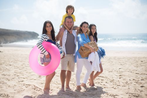 Free A family of five posing happily on a sunny beach in Portugal, capturing summer memories. Stock Photo