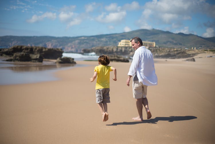 Father And Son Walking On The Beach