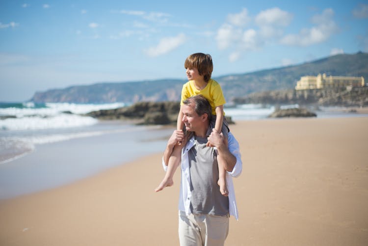 A Father Carrying His Son On His Shoulders 