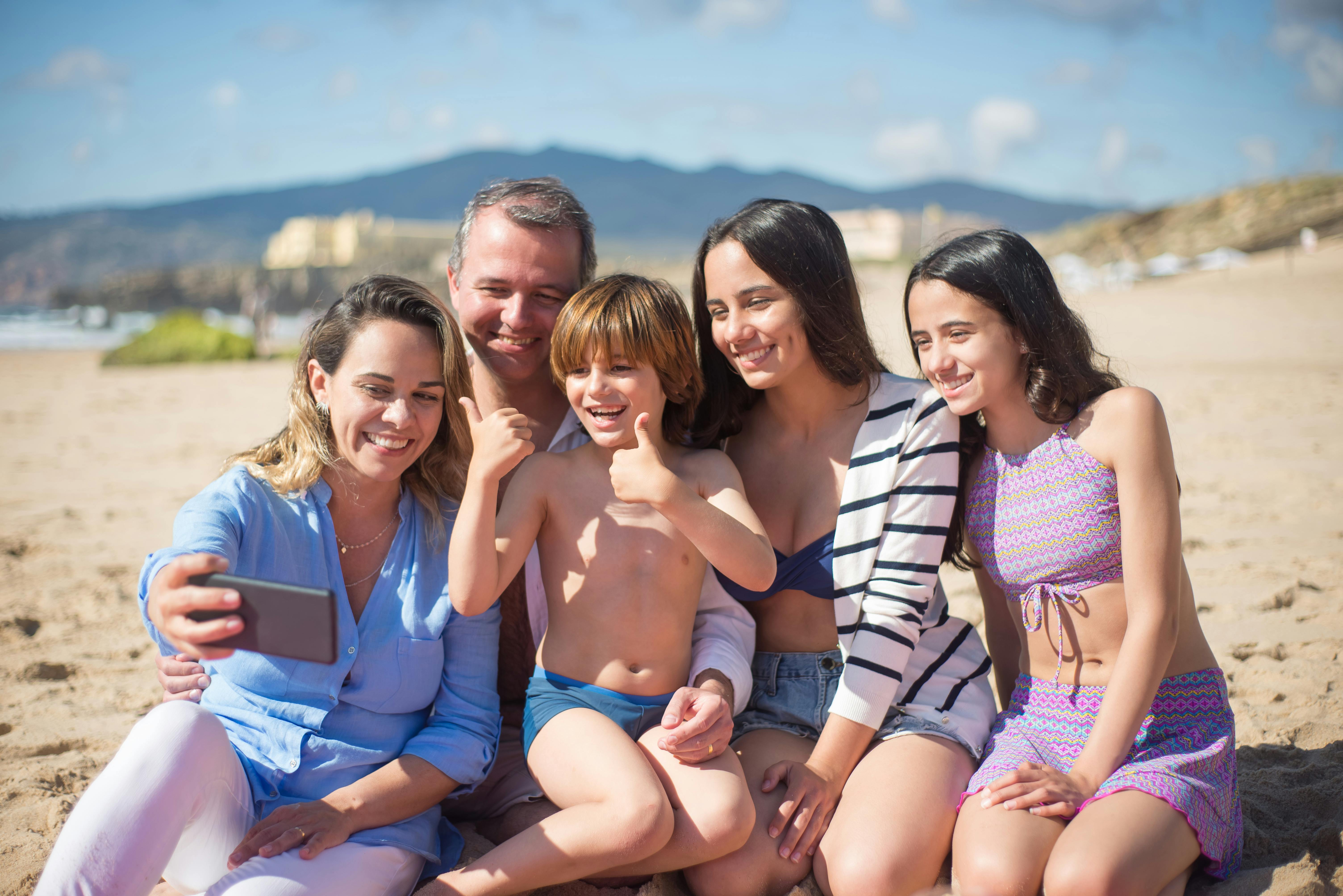 Family smiling and taking a selfie on a sunny beach in Portugal. - Photo by Kampus Production on Pexels