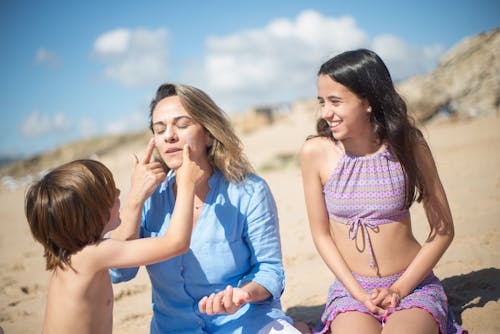 Free Boy Putting Sunscreen on Mother Face Stock Photo