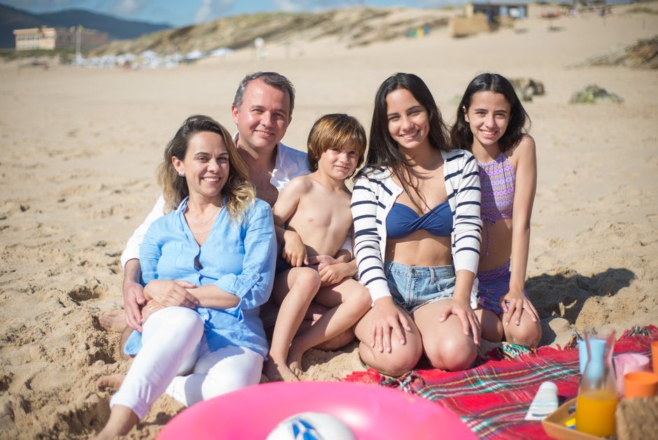 Familia sonriente disfrutando de un día soleado en la playa en Portugal.