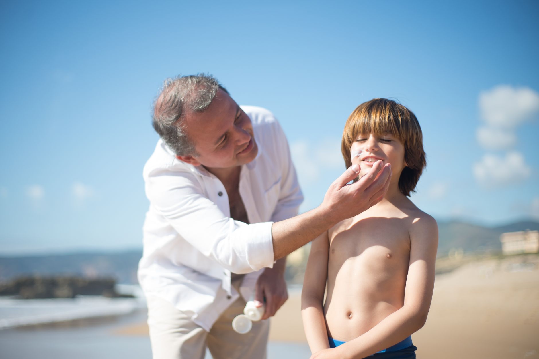 man applying sunscreen face mirror