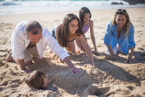 A Family Covering a Boy with Sand on the Seashore