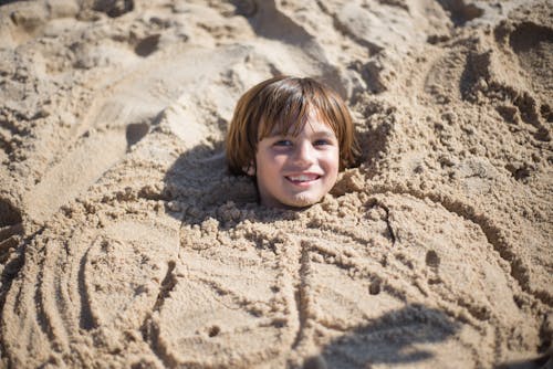 A Young Boy Covered with Sand on the Beach