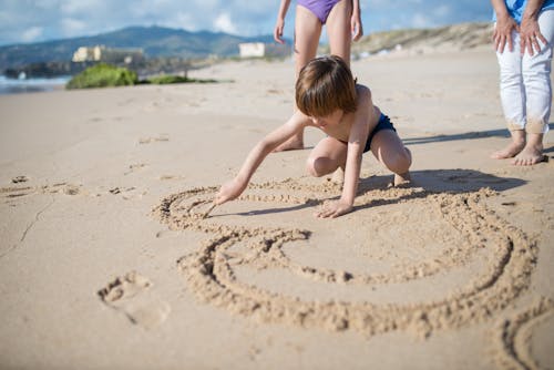 Free Boy Drawing in Sand with Stick Stock Photo
