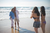 一对快乐的夫妇在葡萄牙阳光明媚的海滩上摆姿势拍照，背景是海浪和沙子