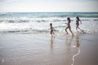 在一个温暖的夏日跑通过波浪的快乐的孩子在一个沙滩