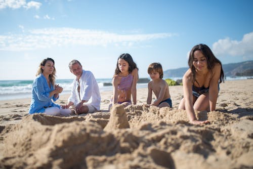 Free A Family Hanging Out Building a Sand Castle on the Beach Stock Photo