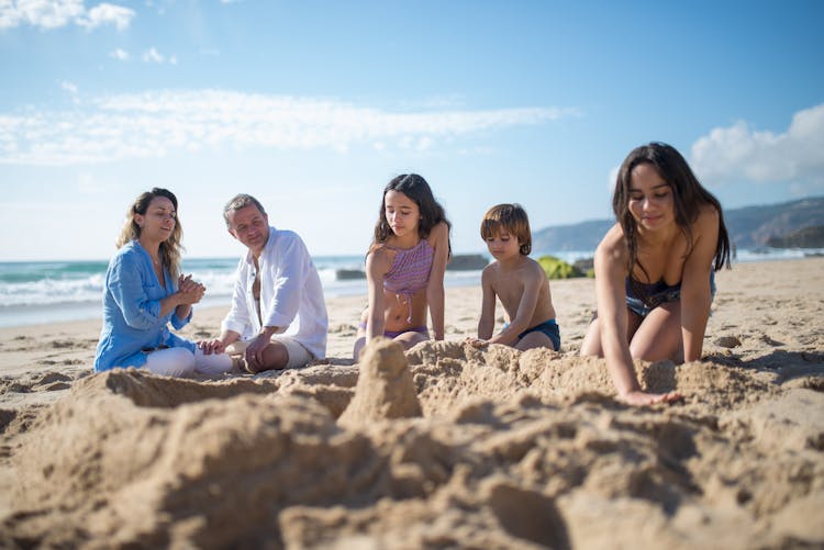 A Family Hanging Out Building A Sand Castle On The Beach