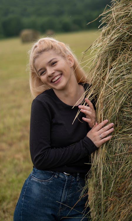 Smiling Blond Girl Posing by a Haystack