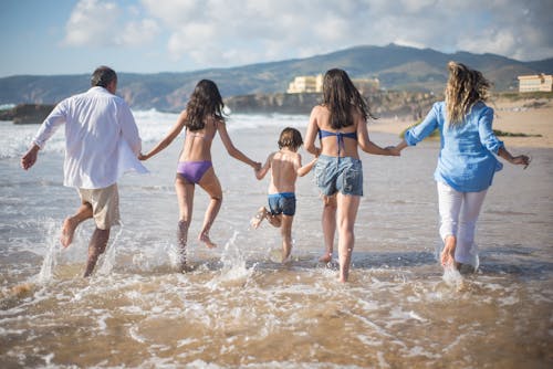Free A Family Having Fun on the Shore with Water Stock Photo