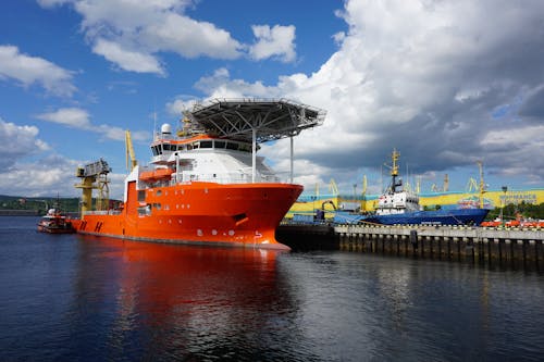 An Orange and White Ship Docked on Pier