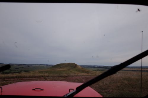 Free View of a scenic countryside through a vehicle windshield, capturing rolling hills under a cloudy sky. Stock Photo