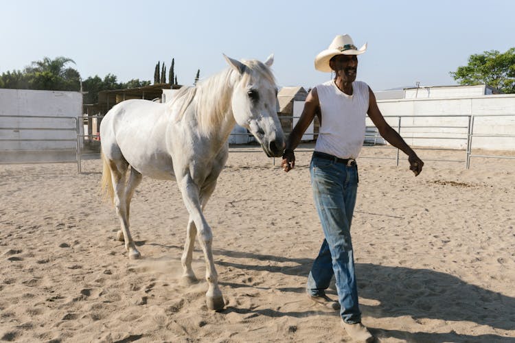 A Man And A Horse Walking In A Horse Pen