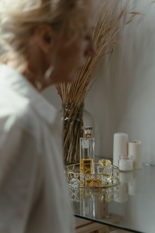 Free A serene room featuring a tray of perfume and candles, with blurred elderly presence. Stock Photo