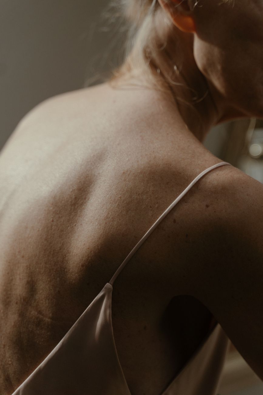 A close-up view of a woman's back with soft, natural light highlighting the skin texture.