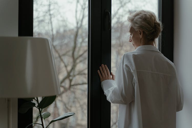 An Elderly Woman Looking Through The Window