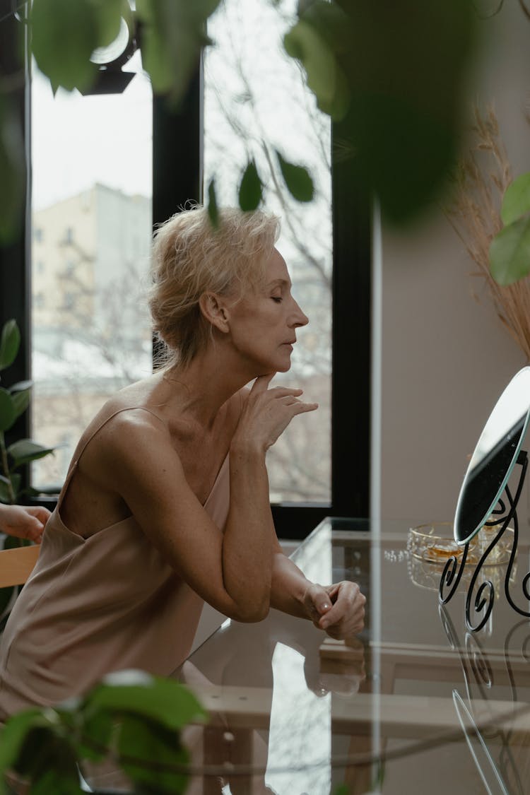 A Beautiful Elderly Woman Looking At Herself In A Mirror