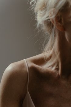 Close-up of a woman's collarbone showcasing natural freckles and texture, with soft lighting accentuating details.